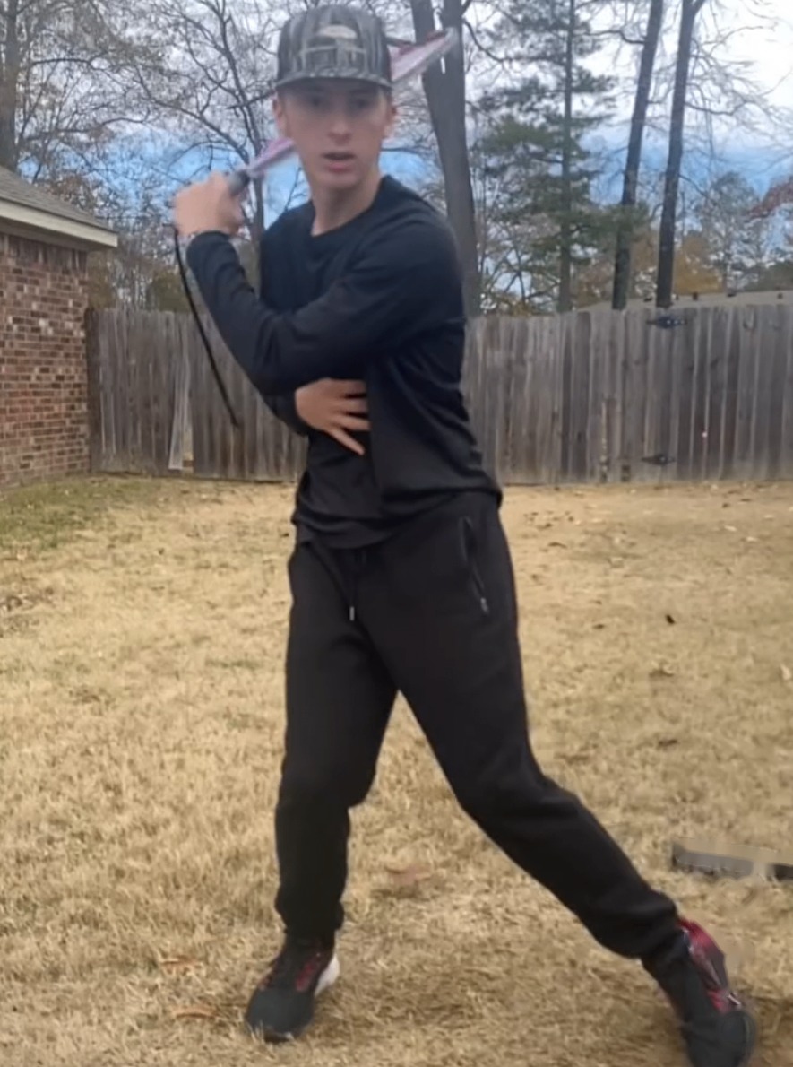 A young athlete taking a full swing in the backyard