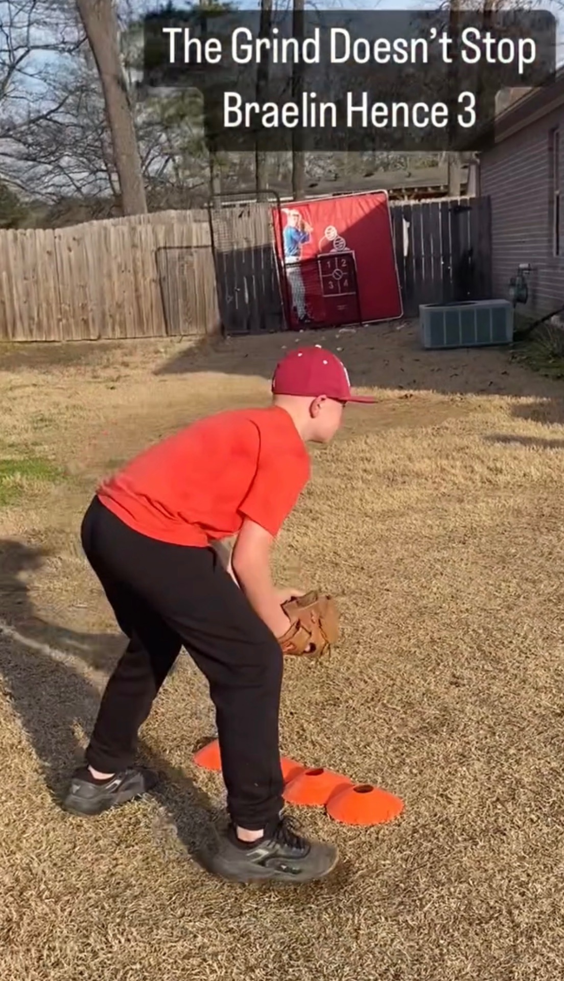 A young athlete in a ready fielding stance with a glove between training cones