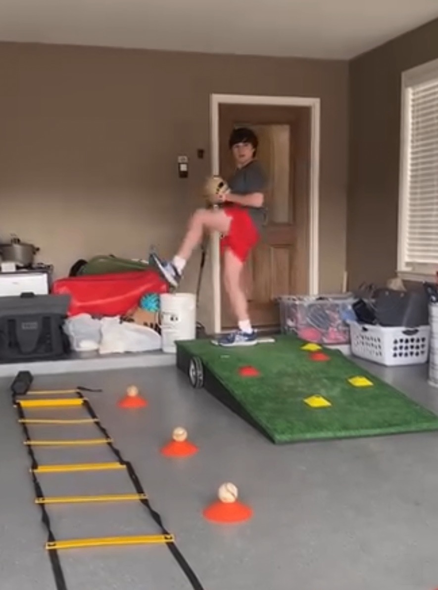 A young athlete training on an agility ladder with cones and a turf ramp in the garage