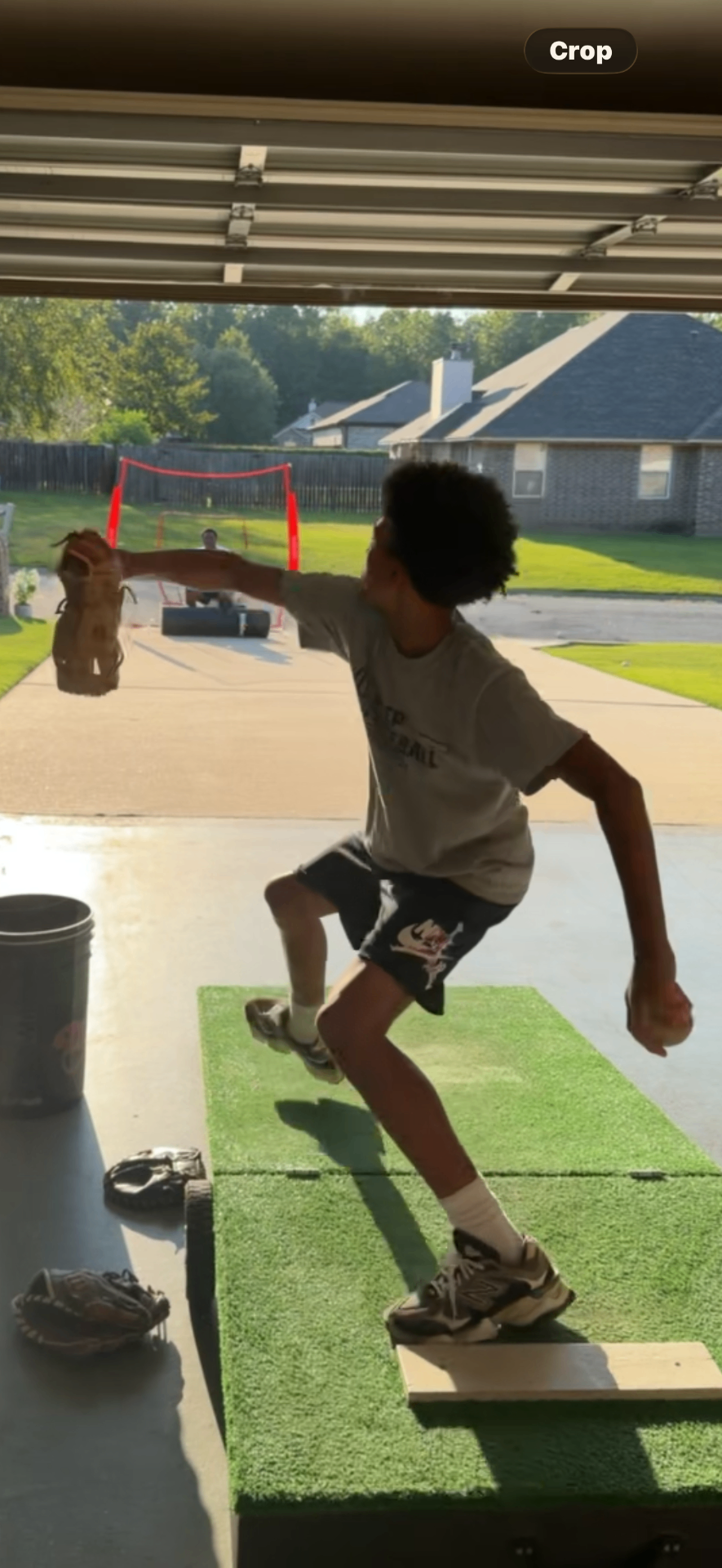A young pitcher throwing off a portable mound toward a net