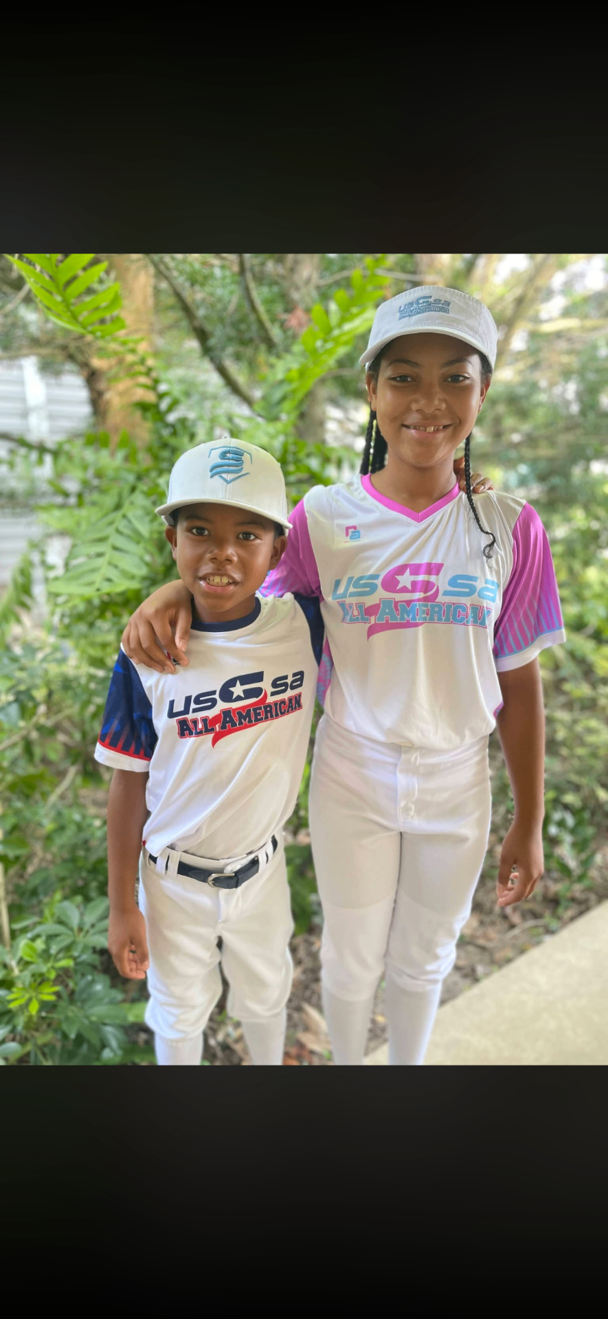 Two young baseball players in USA All American uniforms standing together outdoors